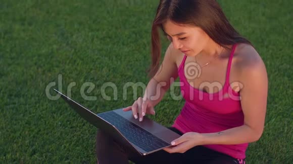带笔记本电脑的学生在草地上用笔记本电脑的亚洲女人视频的预览图