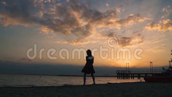 女孩在日落时在海滩上跳舞慢动作视频的预览图