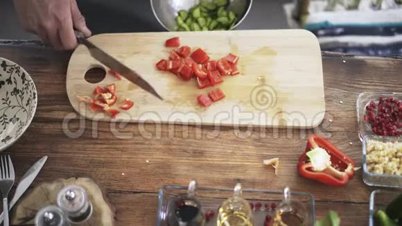 一位厨师将切好的红铃椒放入带有黄瓜的金属碗中俯视图视频的预览图