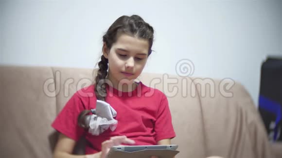 在平板电脑上工作的女孩坐在房间里的沙发上青少年社交媒体网络在平板电脑上玩游戏视频的预览图