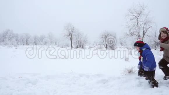三个孩子一起在冬天的风景上跑步慢动作视频的预览图