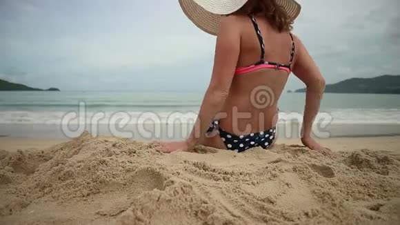 可爱的女人穿着白色宽边躺在阳光明媚的沙滩上视频的预览图