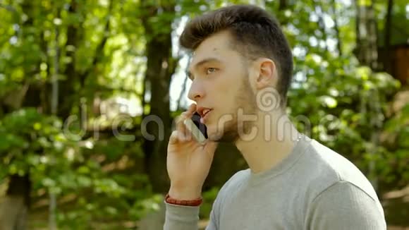 年轻的帅哥在公园里用手机说话视频的预览图