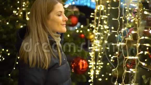 美丽迷人的女人站在一个装饰着花环的橱窗附近新年圣诞节视频的预览图