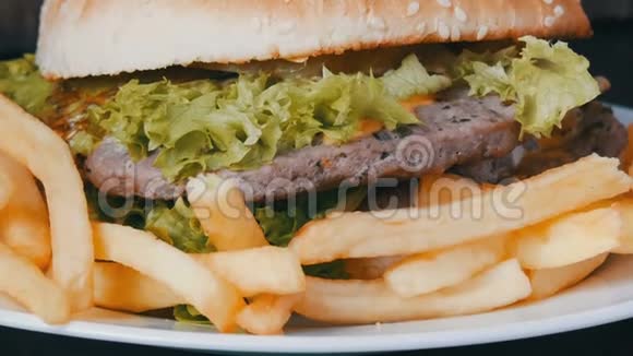 大的三人汉堡有生菜叶和薯条在一个白色的盘子时尚木制背景汉堡视频的预览图