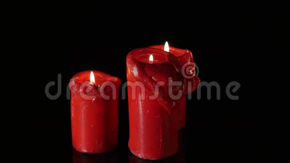 关闭3支点燃的红色蜡烛围绕黑色背景旋转视频的预览图