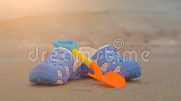 蓝色儿童拖鞋在沙滩上海上背景视频的预览图