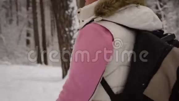穿着温暖运动服的女人手里拿着背包积极地走在森林里的小径上视频的预览图