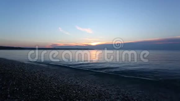 日出时有平静的大海和鹅卵石的海滩视频的预览图