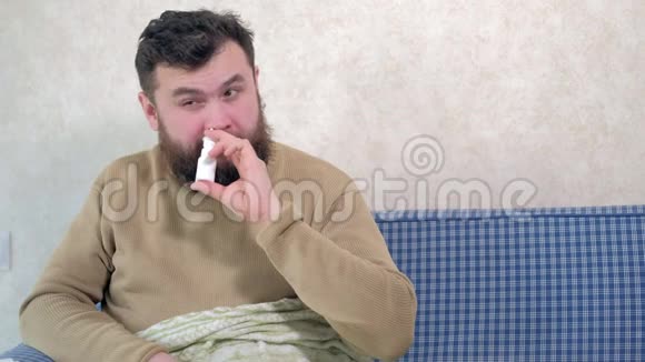 一个感冒的人坐在沙发上他在鼻子里喷了一种特殊的鼻腔喷雾剂视频的预览图