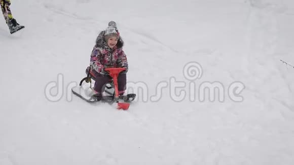 幸福的小女孩坐在她的红色雪橇上从山上滑下来小公主花了她的钱视频的预览图