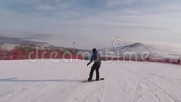 年轻人在高山的背景下从事一项极限运动一个滑雪者在下面的雪坡上跑步视频的预览图