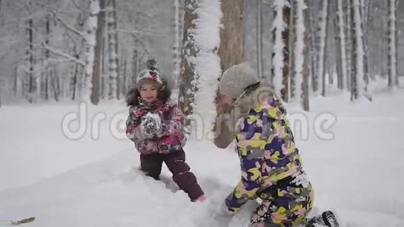 小女孩和她年轻的母亲在公园的户外雪地里玩耍快乐的孩子喜欢冬天很漂亮视频的预览图