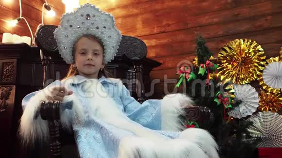 小女孩坐在靠近壁炉的木椅上视频的预览图