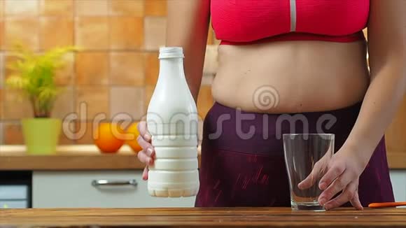 运动女孩把杏仁牛奶倒进厨房的玻璃杯里慢动作视频的预览图