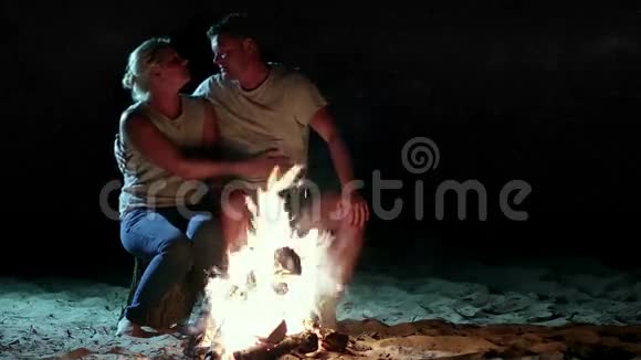 晚上露营时一对浪漫的情侣在火边视频的预览图