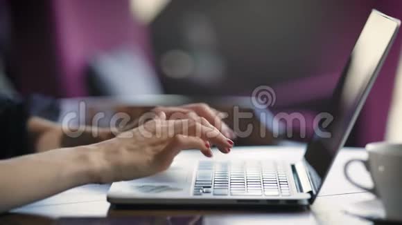 用红色指甲在笔记本电脑键盘上输入文字的女性优雅的双手合上年轻的女商人正坐在视频的预览图