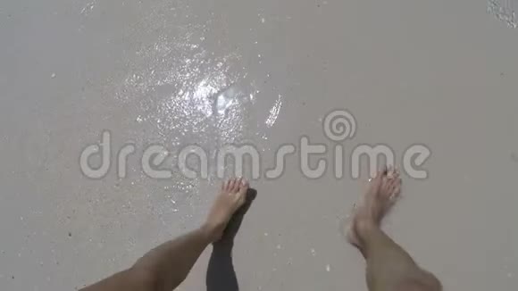 在海滩上清澈的海水中行走的男女双脚特写镜头动作镜头一对一对慢慢地踩着视频的预览图