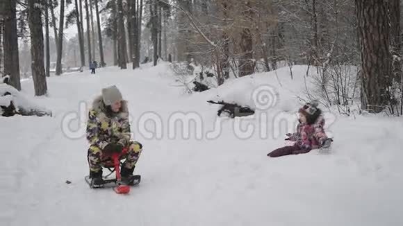 妈妈和女儿在树林里那个女人骑着雪橇在托儿所她心情很好小小的视频的预览图