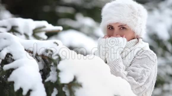 针织毛衣和皮帽穿着迷人的女性温暖她冰冻的手指视频的预览图