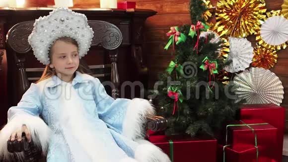 小女孩坐在靠近壁炉的木椅上视频的预览图