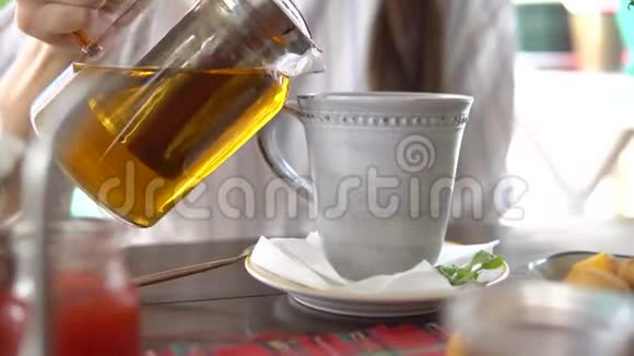 喝茶女人把茶从茶壶倒到杯子里视频的预览图