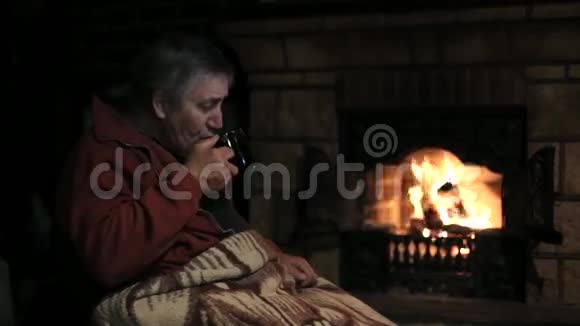 坐在壁炉前喝茶的老人视频的预览图