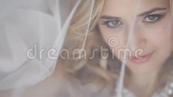 年轻的红发女子新娘穿过婚礼面纱看着相机视频的预览图