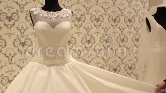 一位年轻漂亮的女士在一家婚纱店里挑选一件白色的礼服视频的预览图