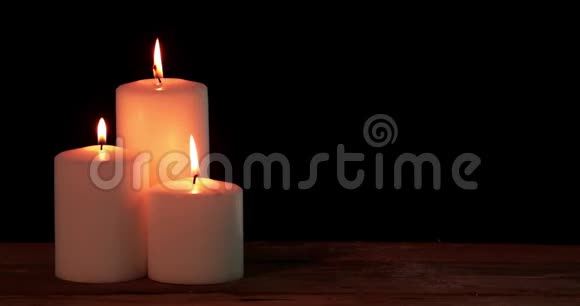 三支白色圣诞蜡烛在桌子上发光视频的预览图