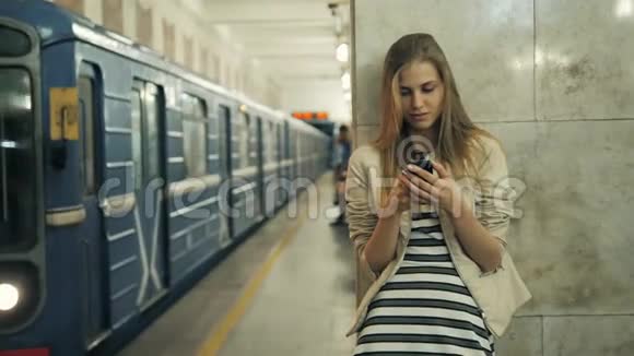 在火车站带智能手机的女孩一位年轻的白种人妇女的肖像在等待着视频的预览图