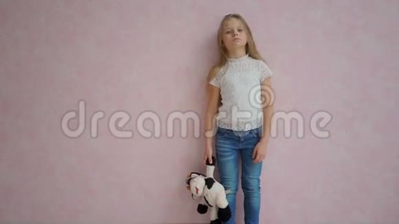 可怜的小女孩长着长发站在粉红色的墙边拿着玩具视频的预览图