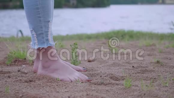 赤脚的女孩走在沙质河岸视频的预览图