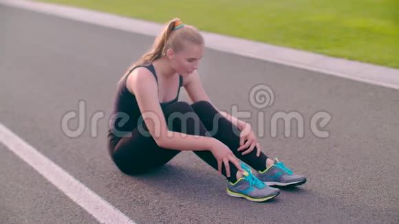 疲惫的跑步者坐在沥青路上精疲力竭的女性跑步者呼吸困难视频的预览图