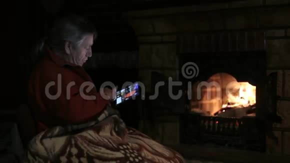 坐在壁炉旁用平板电脑的老人视频的预览图
