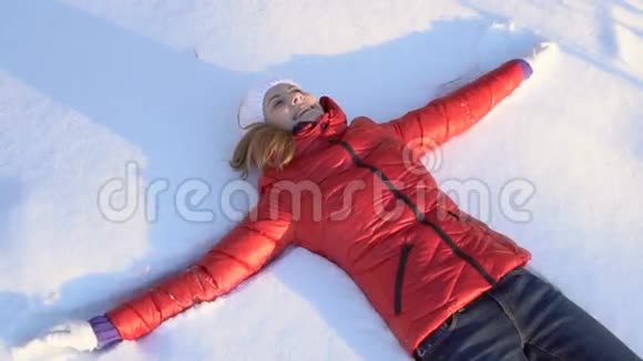 美丽的年轻女子在冬天的公园里做雪天使玩得很开心微笑着慢动作视频的预览图
