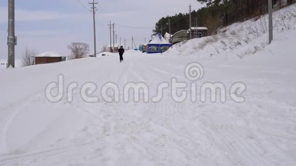 十几岁的男孩在铺满雪的路上奔跑冬季公园儿童假期活动视频的预览图