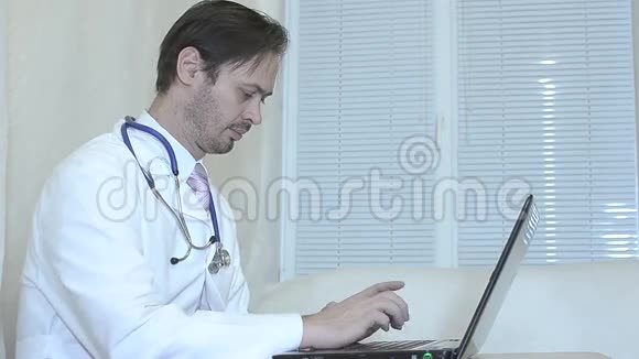 医生在办公室里用笔记本电脑工作穿白大褂打领带的男人在办公室里用笔记本电脑工作视频的预览图