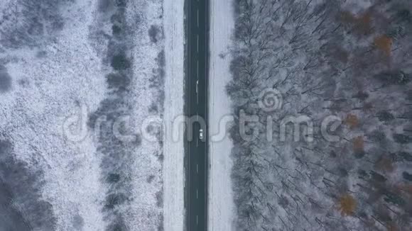 恶劣天气下通过冬季森林的道路交通鸟瞰图视频的预览图