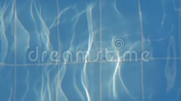 一条漂亮的蓝色踏板的女性腿沿着游泳池走泳池里的蓝色水阳光反射视频的预览图