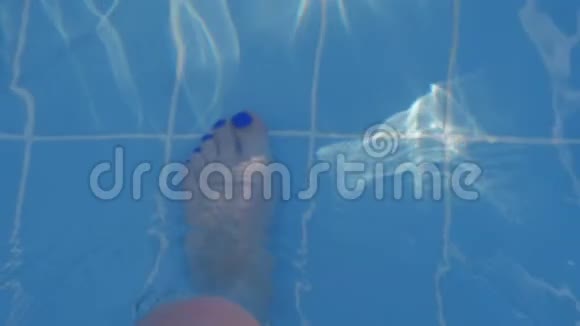 一条漂亮的蓝色踏板的女性腿沿着游泳池走泳池里的蓝色水阳光反射视频的预览图