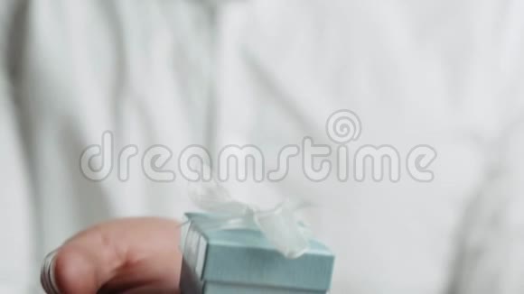 男性双手漂亮地拿着一个白色背景的小礼盒呈现出快乐视频的预览图