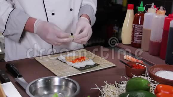 厨师用黄瓜和红鱼子酱做美味的寿司卷视频的预览图