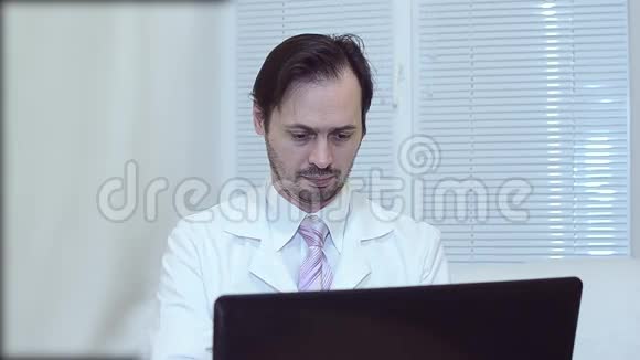 穿着白色外套和领带的人在办公室工作在笔记本电脑上工作医生在办公室工作视频的预览图
