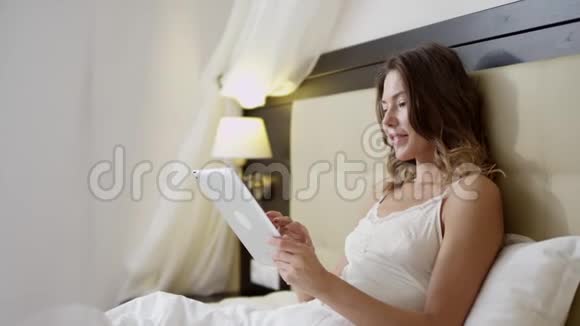 女人在床上用平板电脑视频的预览图