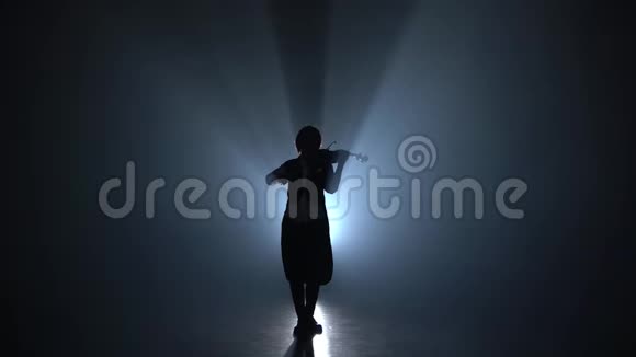 女孩在一个阴暗的烟雾弥漫的房间里拉小提琴这是一首经典的乐曲轮廓黑烟背景视频的预览图