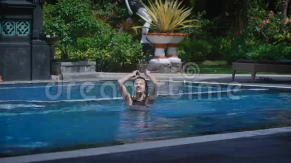 在炎热的夏日黑发女人正在巴厘岛度假胜地的游泳池里跳着水年轻快乐的女孩视频的预览图