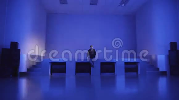 一个年轻人独自坐在空荡荡的舞池里用笔记本电脑邀请朋友参加聚会视频的预览图