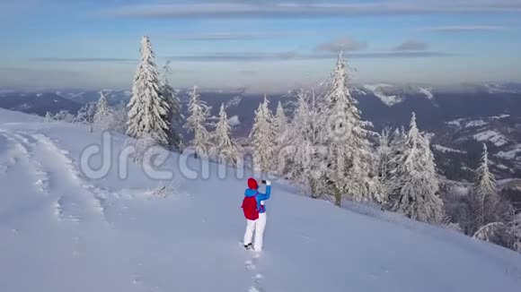 飞越孤独的旅游女孩在智能手机上拍摄大自然的照片晴朗的霜冻天气视频的预览图