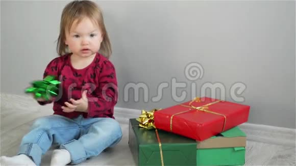 可爱的小女孩坐在明亮的盒子附近女孩打开礼物有兴趣的婴儿检查盒子上的礼物视频的预览图